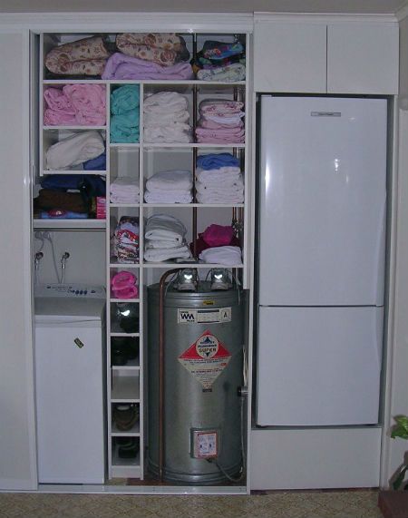 Tidy laundry storage solution in the kitchen of a home in Thames, New Zealand. Includes sliding doors and shelves for extra storage.